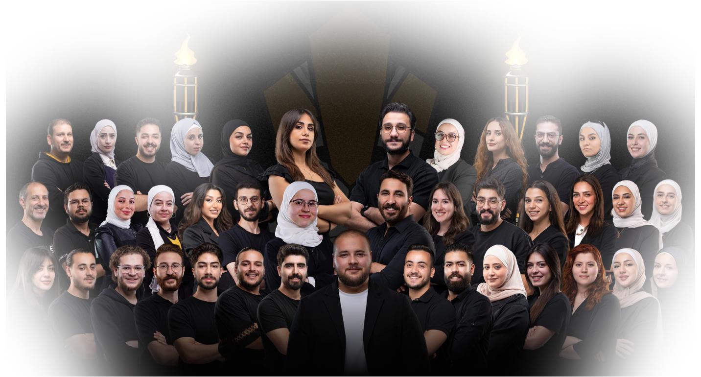 Group portrait of diverse young adults and professionals posing together against a black background with two burning torches.